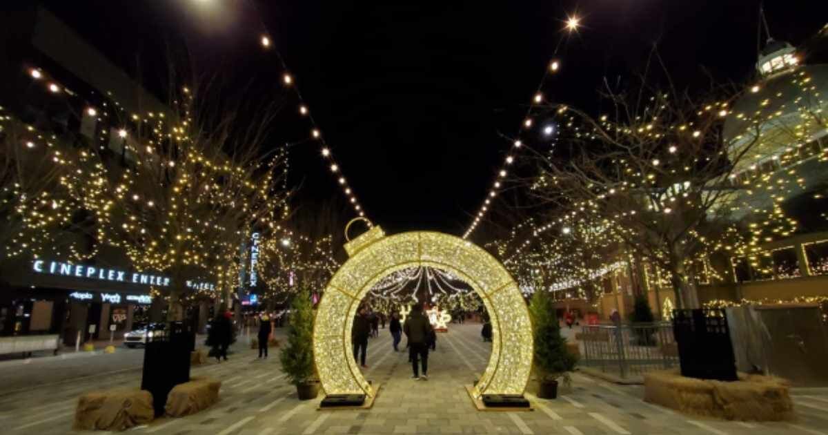 Light-up archway: A glowing ornament-shaped archway on a festive street with string lights.